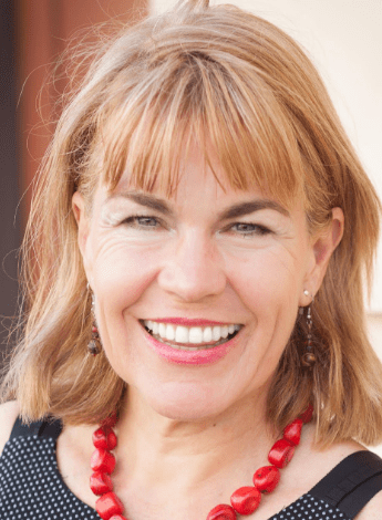 A blonde-haired woman with a thick fringe wearing a chunky red necklace